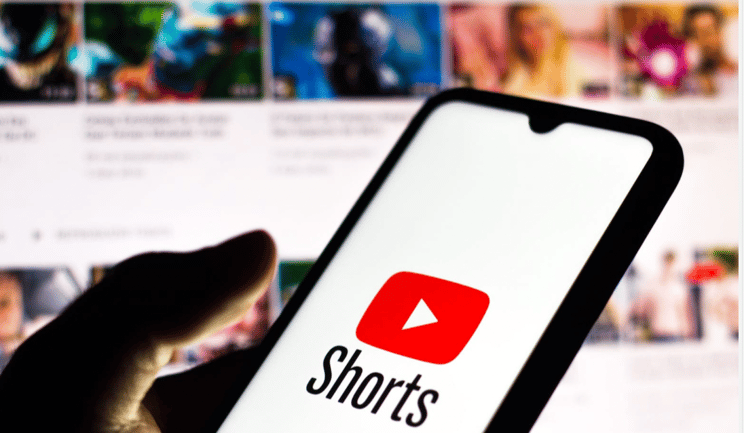 person holding phone with youtube shorts logo 